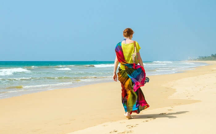 a lady wearing colourful clothes walking on a beach ss01052018
