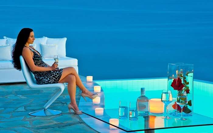 a woman enjoying champagne on the terrace of a resort in Greece