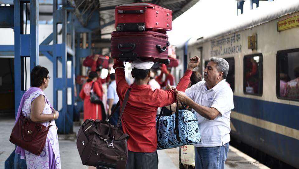 a coolie carrying luggage at a railway station 