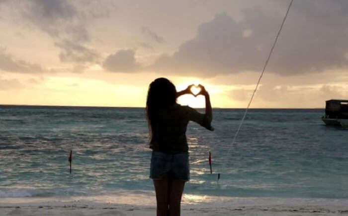girl making heart on the beach