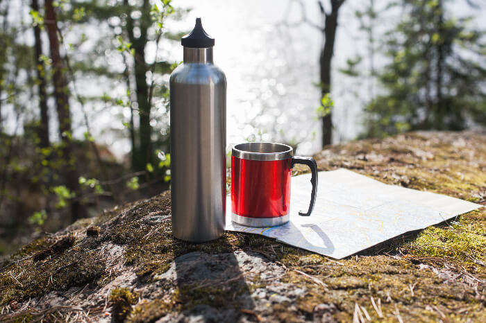 Thermal bottle and mug placed on the side of a hill