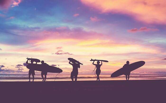 people carrying surfing boards at El Porto Beach 