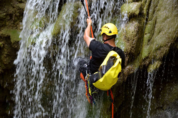 A man rappelling down a waterfall 