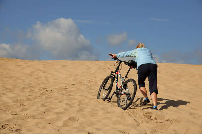 A person hiking the sand dunes with a cycle