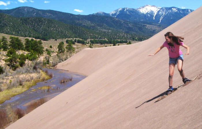 A woman sand-boarding at Great Sand Dunes National Park