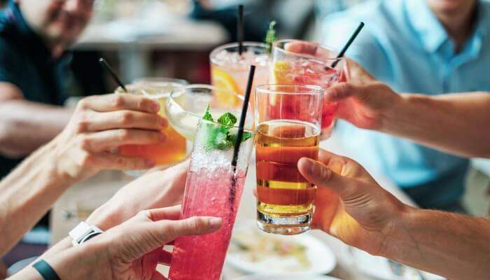 people clinking their glasses with cocktail and mocktail