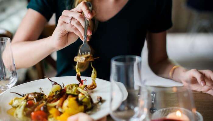 a lady taking food from the plate with a fork