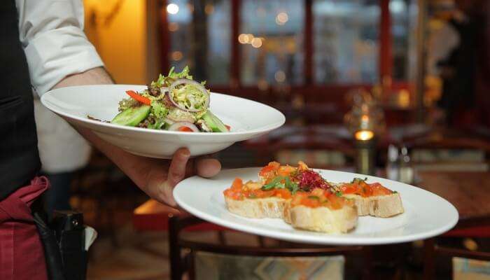 dishes being served by a waiter 