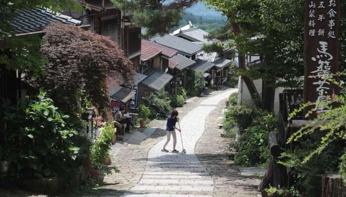 lady brooming a street in a hill station