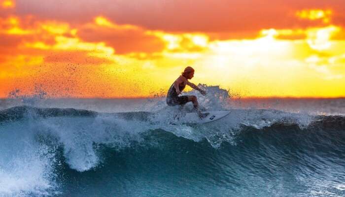 man surfing while the sun sets in the backdrop