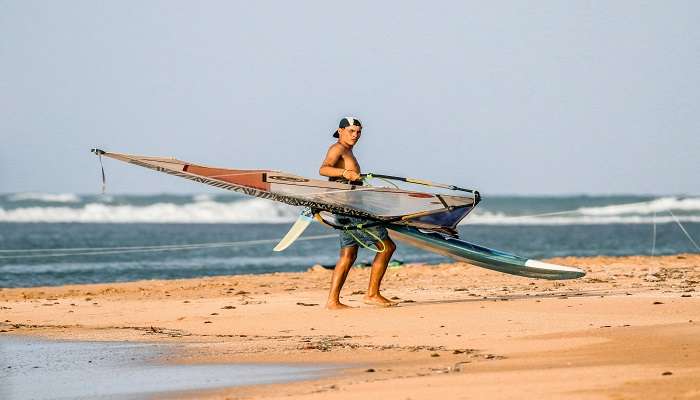 A man carrying a windsurfing board