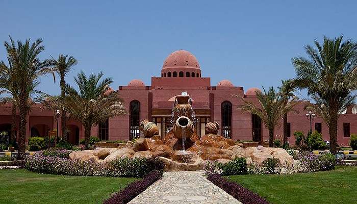 A grand view of Hotelux Oriental Coast Marsa in
egypt with a medieval architectural style and a big fountain in front of the entrance. 