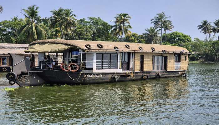 Backwater houseboat in Kerala amidst lush greenery.