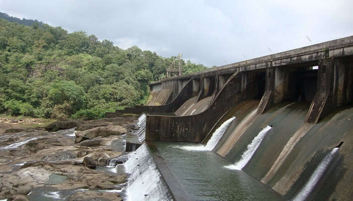 Peringalkuthu Dam reservoir with forest backdrop near Athirapally waterfalls.