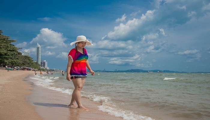 Girl in Hat and Bright Top Walking on the Beach