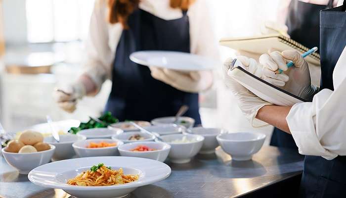 A picture of students taking notes while learning how to cook.