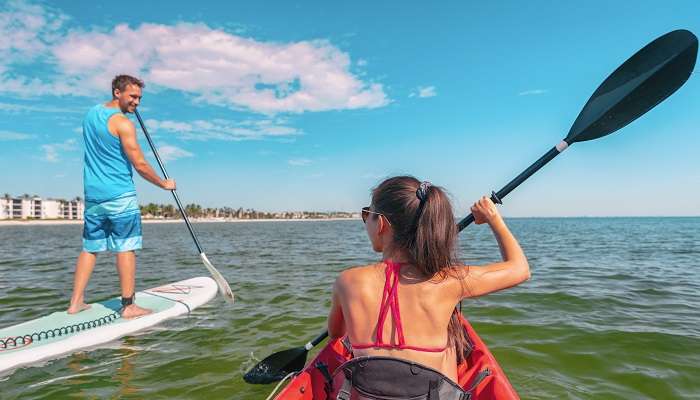 Couple kayaking and paddleboarding on calm waters in Phuket Beach.