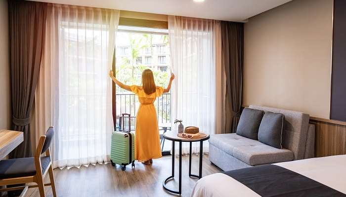 Young woman tourists opening the window curtain in the morning