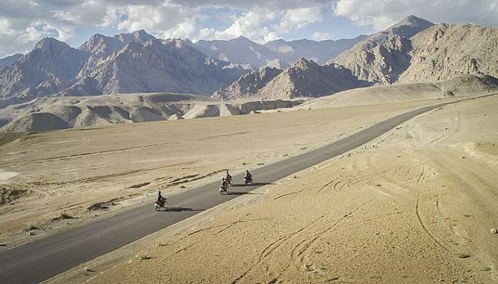 The road that is surrounded by mountains leads to Kaza