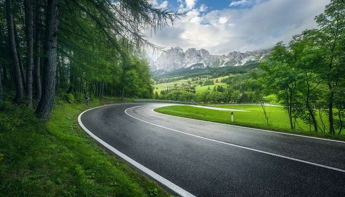 A road in a green forest on a rainy day in nohsngithiang falls.