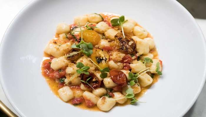 Tasty gnocchi with tomatoes and herbs on plate