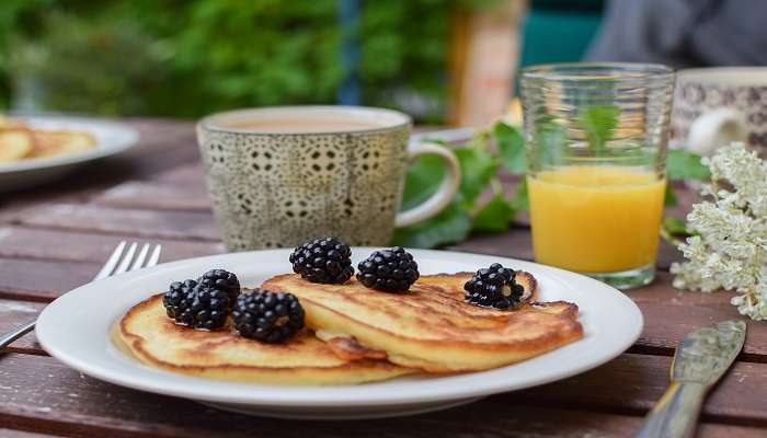 Fresh pancakes with orange juice and a cup of cappuccino on the side.