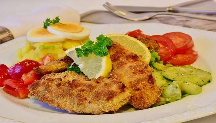 A delicious spread of chicken schnitzel with eggs and salad on the side.