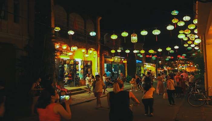 Mi Quang, a traditional Vietnamese dish, enjoyed at Hội An Night Market amidst vibrant street food stalls.