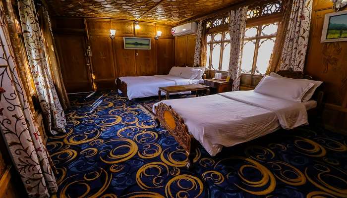 two double beds in the room with blue carpet and wooden walls