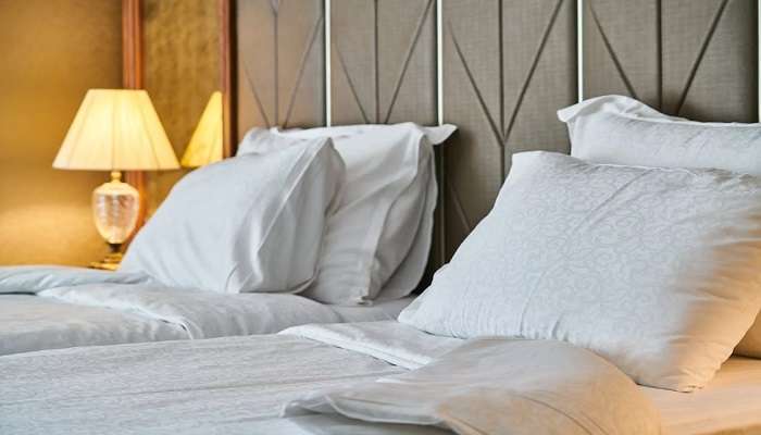 A bed in white linen in a hotel in Kuniyamuthur.