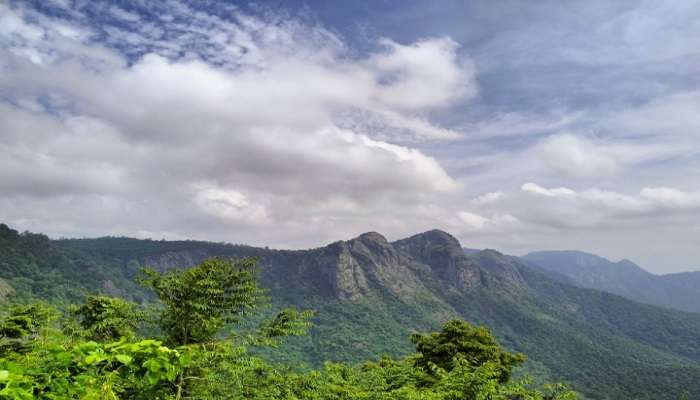 Lush green hills on a cloudy day near the Hotels In Gummidipoondi.