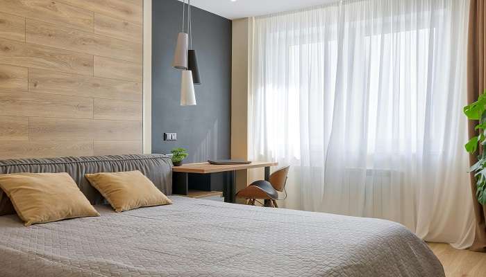 A stunning bedroom with a wooden table near the white curtain at one of the top Hotels in Bendigo.