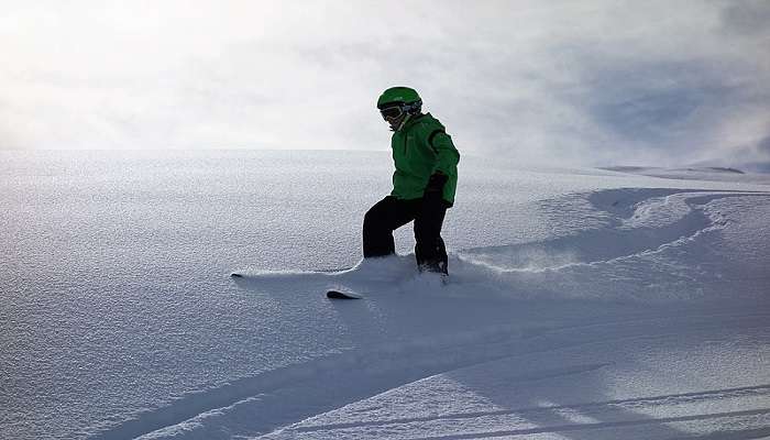 A boy skiing in deep snow without sticks in the Dolomites.