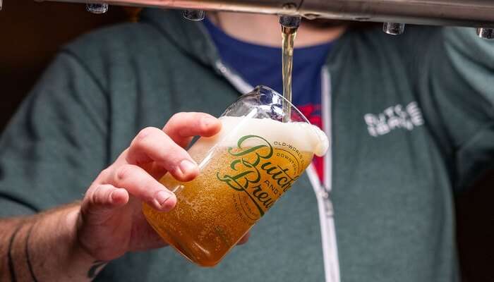 Employee filling beer cup from tap at Butcher and Brewer, Lower Hutt.