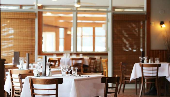 unrecognisable-waiter-serving-pasta-on-table-with-glasses-in-restaurant