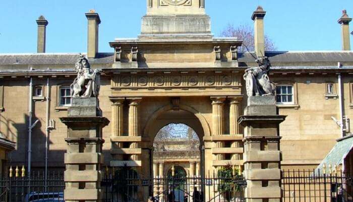 A girl passing the front gate of Royal Mews in Buckingham Palace.