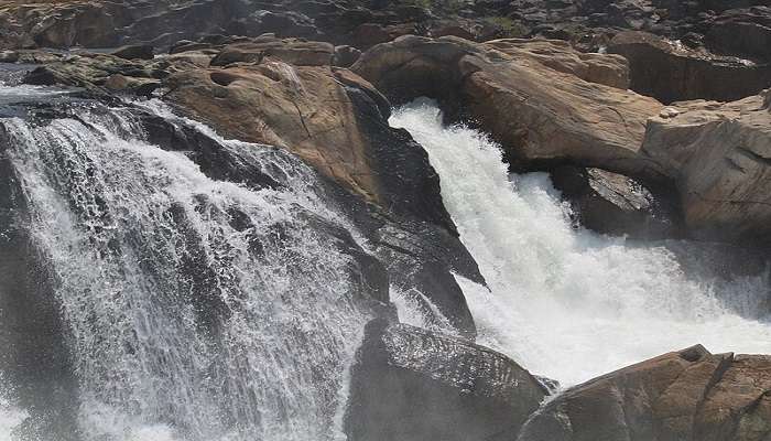 The water of Dhuandhar Falls flows on ancient rocks 