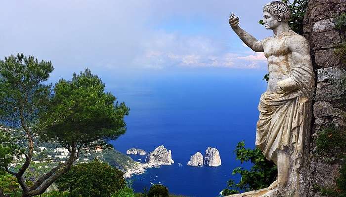 View of Faraglioni rocks in Capri coastline from the Saint Augustus statue on top of the cliff near the Amalfi Coast Italy.