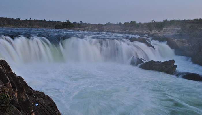 An enchanting picture of Dhuandhar Falls, balancing rock