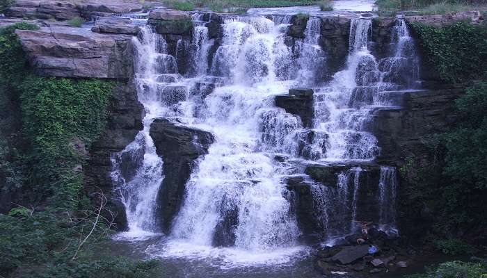 A picture of Ethipothala Falls dropping down a rock face in a green environment.