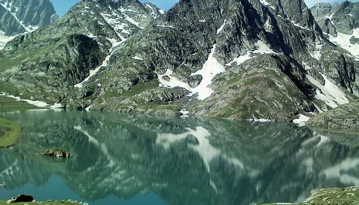 Lush green meadows surround Kishansar Lake.