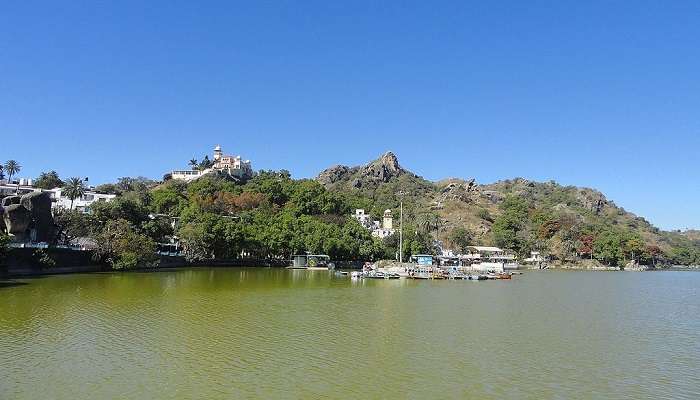 Boats floating in the serene water of Nakki Lake with surrounding hills.