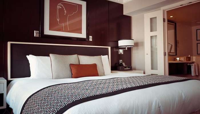 Black and grey bedspread with pillows inside a hotel room 