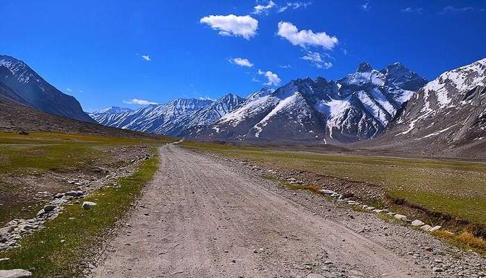 Lush green Suru Valley with snow-capped peaks in the background near the Munshi Aziz Bhat Museum.