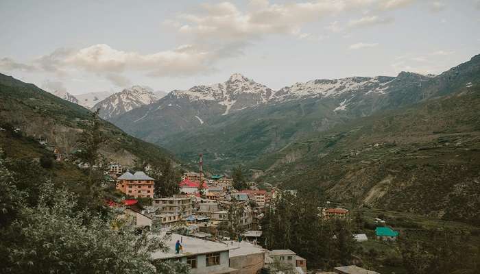 Traditional Himachali Houses in Gushaini village with apple orchards in the foreground near the Tirthan Valley Himachal Pradesh