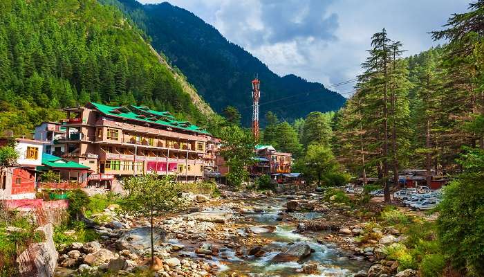 Scenic view of Kasol village with Parvati River running in the middle across pine forests 