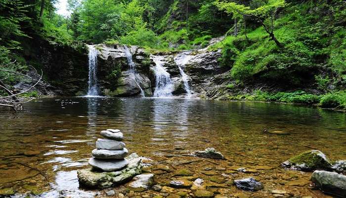 Kovai Kutralam Falls, a scenic waterfall near Coimbatore, surrounded by lush greenery. Visitors enjoy the serene atmosphere, ideal for picnics and nature walks.