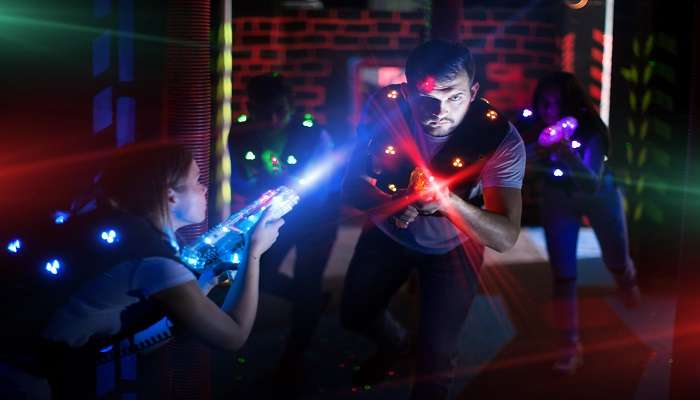 People in colored beams of laser guns during LaserCombat game in the arena 