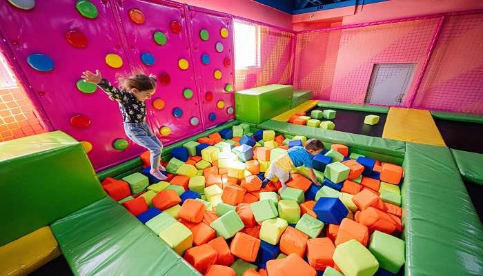 Kids playing at indoor play centre Little Land , jumping in a color cubes pool of Harbor Land 