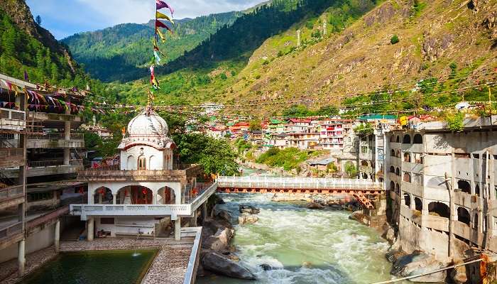 Manikaran Gurudwara with steaming hot springs in the foreground and snow-capped mountains in the background. 